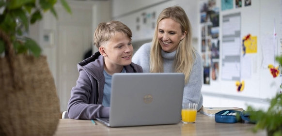 Mor og sønn med PC og Trådløst Bredbånd på kjøkkenet