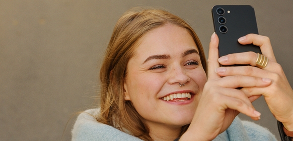 jente som smiler mens hun tar bilde av noe med galaxy s25